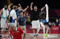 Slovenia's Luka Doncic (77), right, and teammates celebrate on the bench during men's basketball preliminary round game against Japan at the 2020 Summer Olympics, Thursday, July 29, 2021, in Saitama, Japan. (AP Photo/Charlie Neibergall)