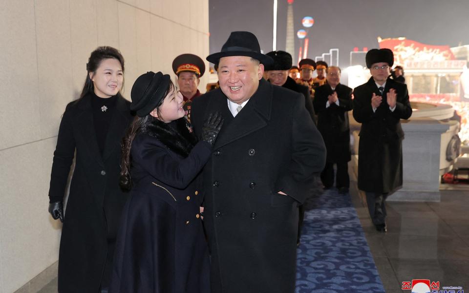 Kim Jong-un, wearing a black coat and fedora, attends the parade with his wife Ri Sol Ju, left, and daughter, 2nd left - KCNA via REUTERS