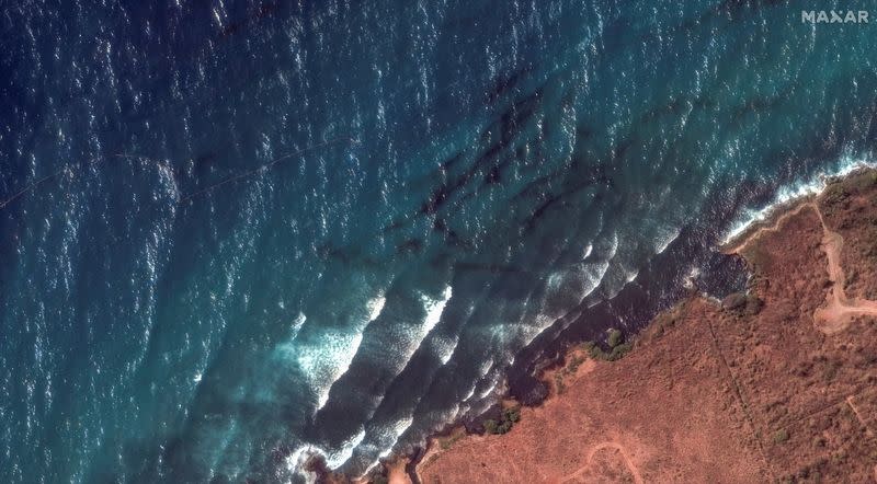A satellite image shows an oil spill on the ocean and a containment boom on the shoreline of Tobago Island
