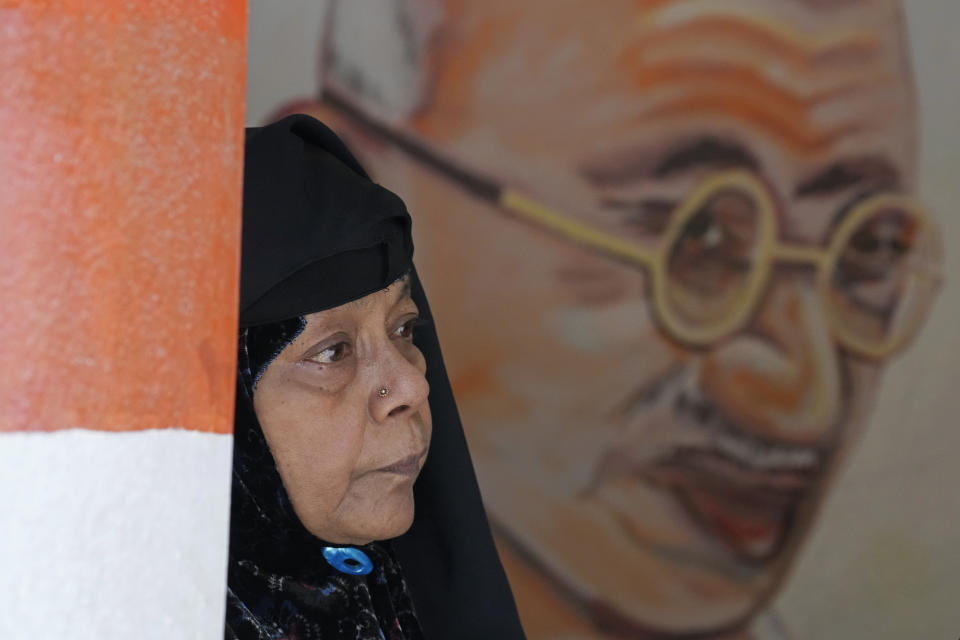 A Muslim woman stands next to a portrait of Mahatma Gandhi as she waits to cast her vote at a polling station in Bengaluru, India, Wednesday, May 10, 2023. People in the southern Indian state of Karnataka were voting Wednesday in an election where pre-poll surveys showed the opposition Congress party favored over Prime Minister Narendra Modi's governing Hindu nationalist party. (AP Photo/Aijaz Rahi)