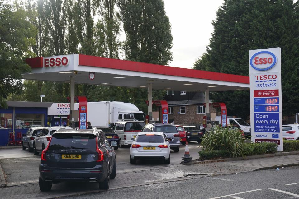 Drivers queue for fuel at a petrol station in Birmingham, England, Tuesday, Sept. 28, 2021. Long lines of vehicles have formed at many gas stations around Britain since Friday, causing spillover traffic jams on busy roads. (AP Photo/Jacob King)