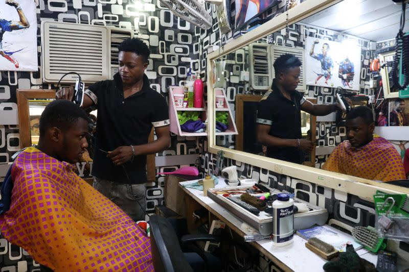 A barber cuts a customer's hair at a barber's shop in Lagos Island