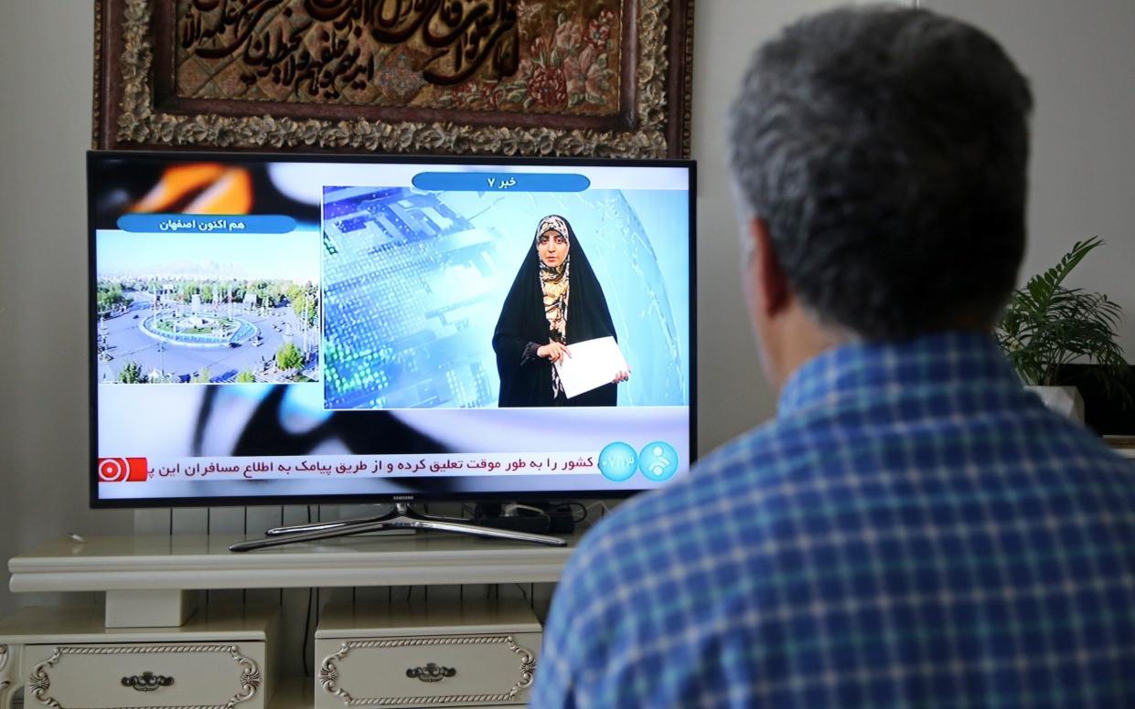 A man watches TV reports in Iran following explosions