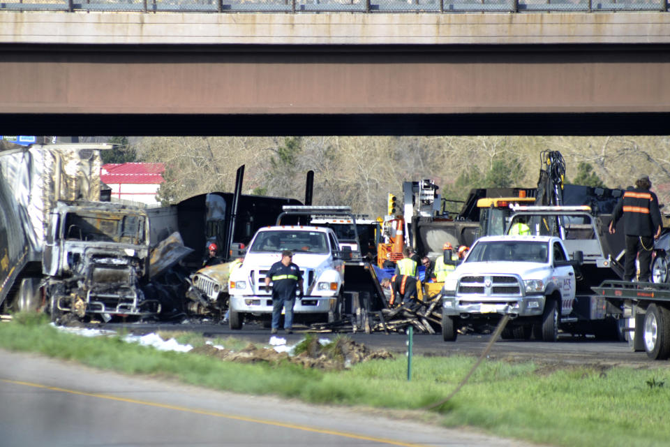 Authorities survey the scene of a fiery crash on I-70 near Colorado Mills Parkway that shut down the highway in both directions on Friday, April 26, 2019. Lakewood, Colo. A truck driver blamed for causing a deadly pileup involving over two dozen vehicles near Denver has been arrested on vehicular homicide charges. Lakewood police spokesman Ty Countryman said Friday that there's no indication that drugs or alcohol played a role in Thursday's crash. (AP Photo/Peter Banda)