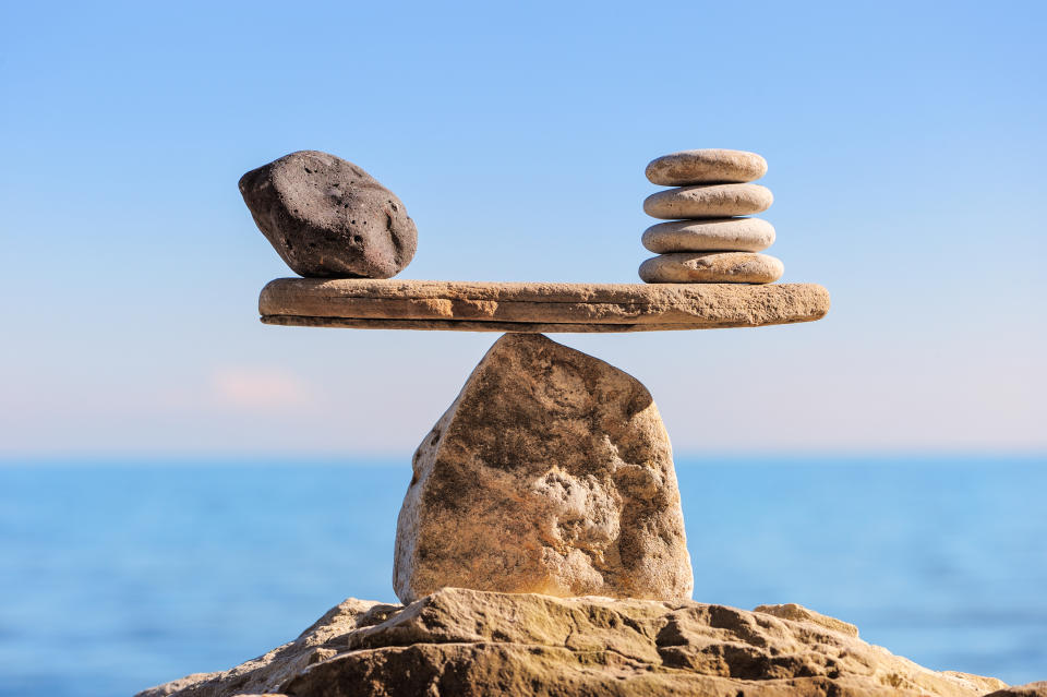 Smaller rocks balanced on a slab balanced on a larger rock.