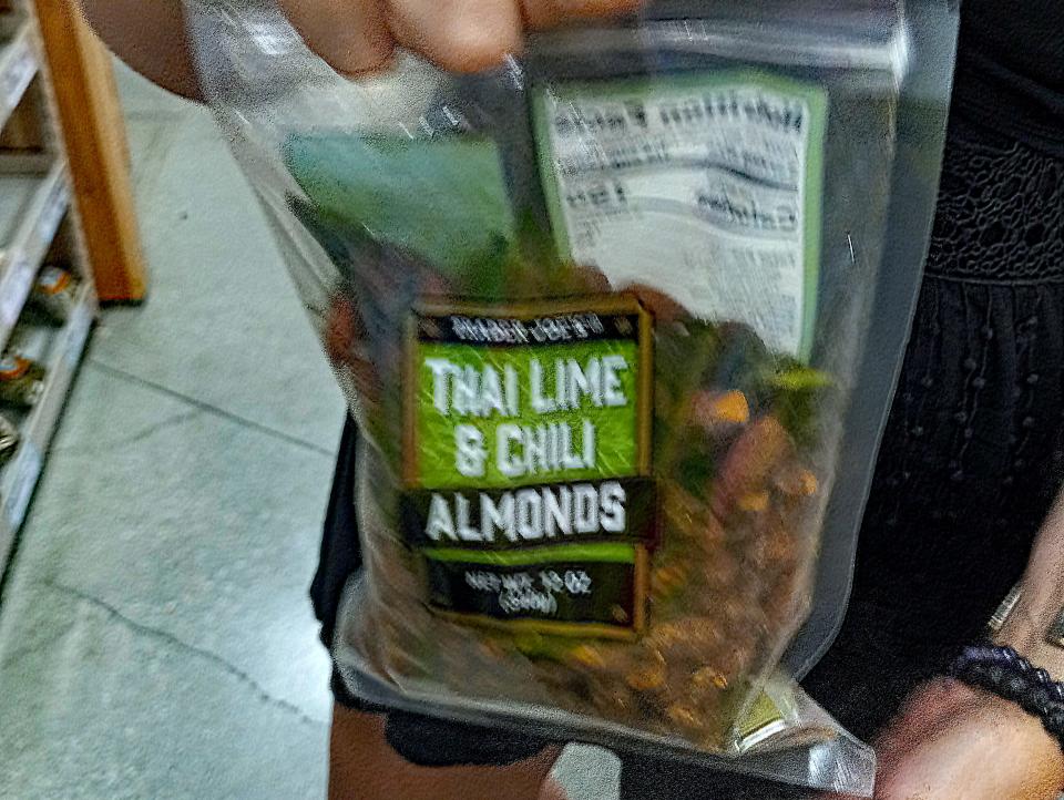 hand holding package of seasoned almonds on the aisle of a trader joes