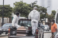 Cemetery workers carry the remains of a person for burial at a cementery in Guayaquil, Ecuador, Monday, April 6, 2020. Guayaquil, a normally bustling city that has become a hot spot in Latin America as the coronavirus pandemic spreads, has untold numbers dying of unrelated diseases that can't be treated because hospitals are overwhelmed. (AP Photo/Luis Perez)