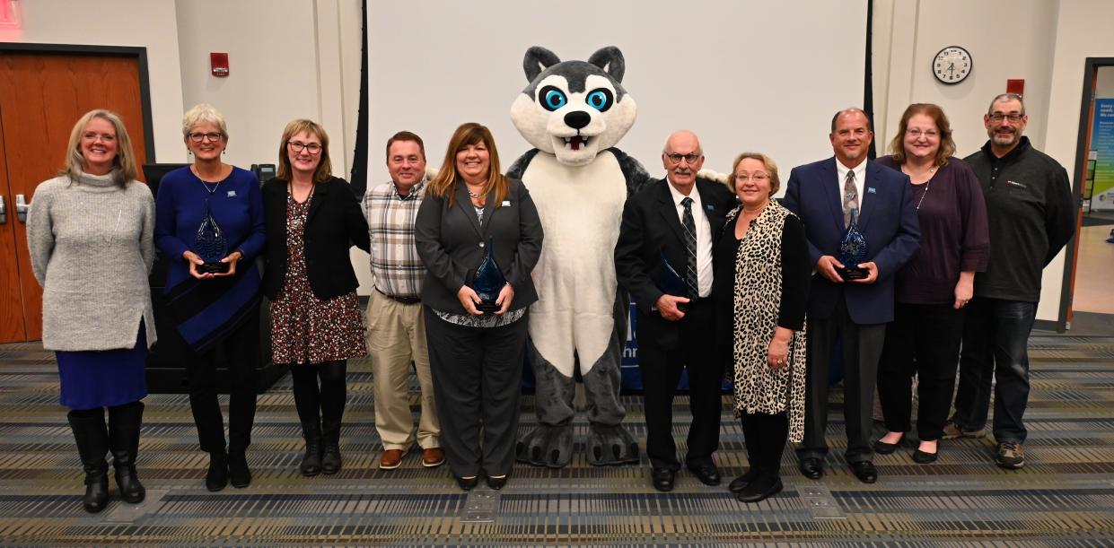 The Alumni Hall of Fame inductees stand with their family members and those who nominated them for this prestigious award. Marion Technical College mascot Enzo, a giant husky, joined the group at the awards ceremony on November 17, 2022 on the Marion Campus.