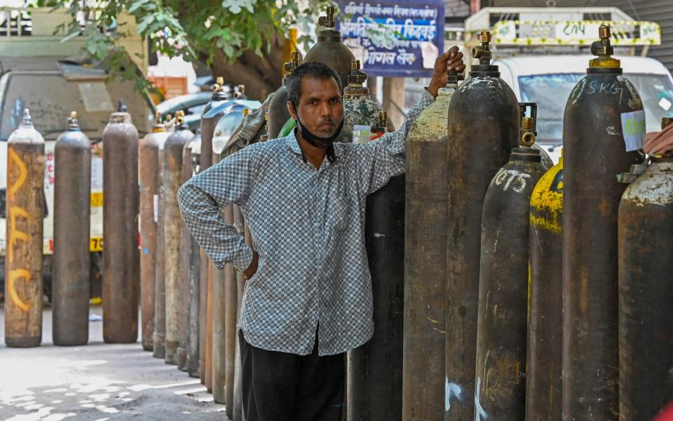 A man waits to refill his medical oxygen cylinder for the Covid-19 coronavirus patient under home quarantine at a private refill centre in New Delhi - PRAKASH SINGH / AFP