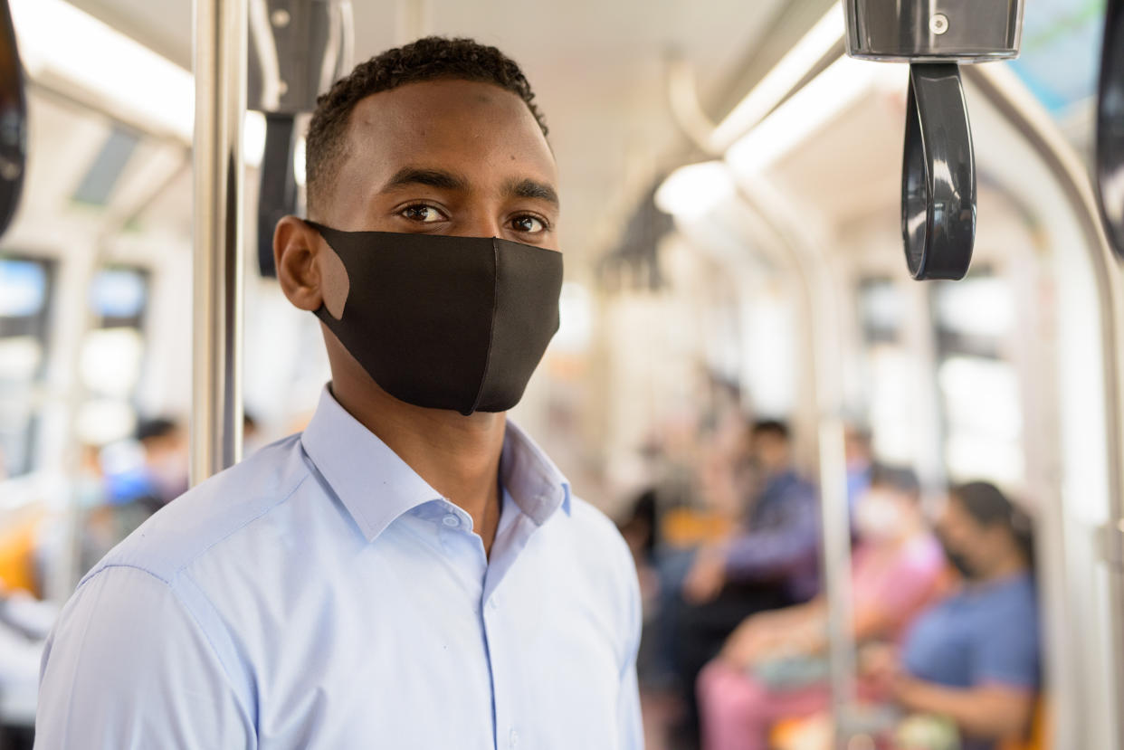 Portrait of young African businessman with mask for protection from corona virus outbreak social distancing inside the train