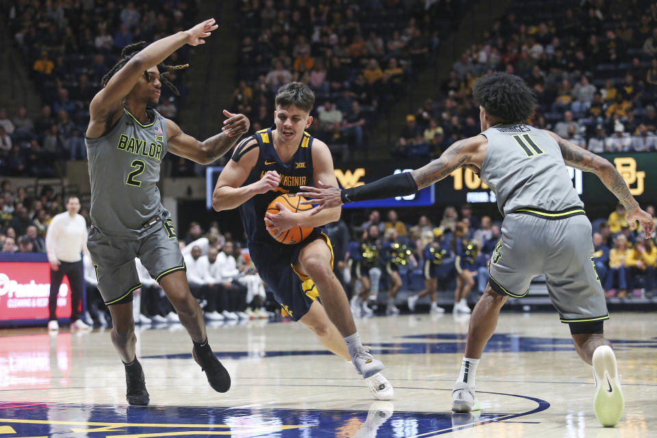 West Virginia guard Kerr Kriisa drives between Baylor guard Jayden Nunn (2) and forward Jalen Bridges (11) during the second half of an NCAA college basketball game Saturday, Feb. 17, 2024, in Morgantown, W.Va. (AP Photo/Kathleen Batten)