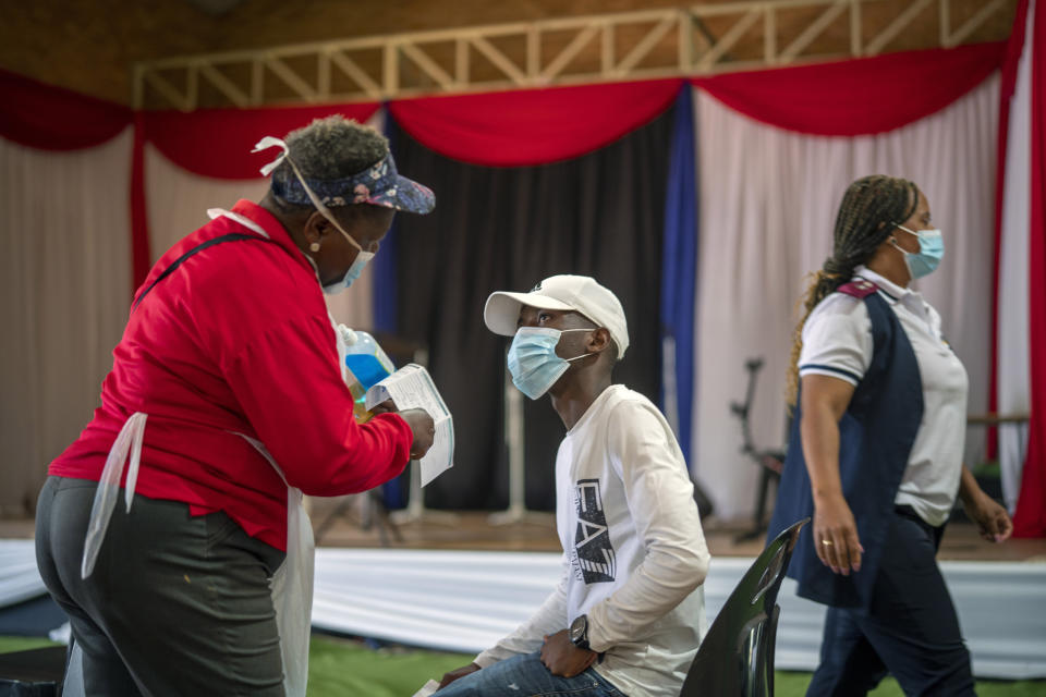 An Orange Farm, South Africa, resident listens to a nurse after receiving his jab against COVID-19 Friday Dec. 3, 2021 at the Orange Farm multipurpose center. South Africa has accelerated its vaccination campaign a week after the discovery of the omicron variant of the coronavirus. (AP Photo/Jerome Delay)