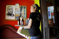 In this June 7, 2020, photo, a portrait of George Floyd hangs in the lobby of Conga Latin Bistro, a Minneapolis club where he worked as a bouncer. His coworker Princis Mercedes carries drinks for customers. (AP Photo/Julio Cortez)