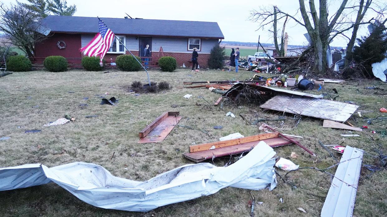 Family members walk out of a storm-damaged home Wednesday morning on Route 56 in Madison County after strong storms blew through about 4 am. No one was injured at this home; three horses and a donkey in a barn on the property were not injured.