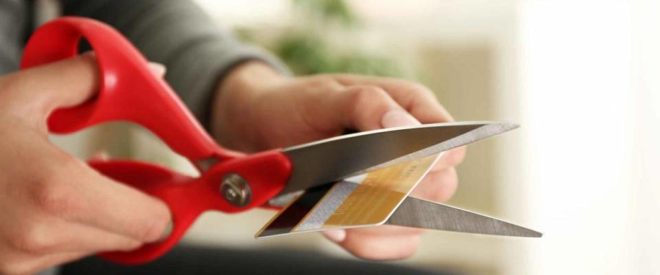 Female hands cutting credit card with scissors