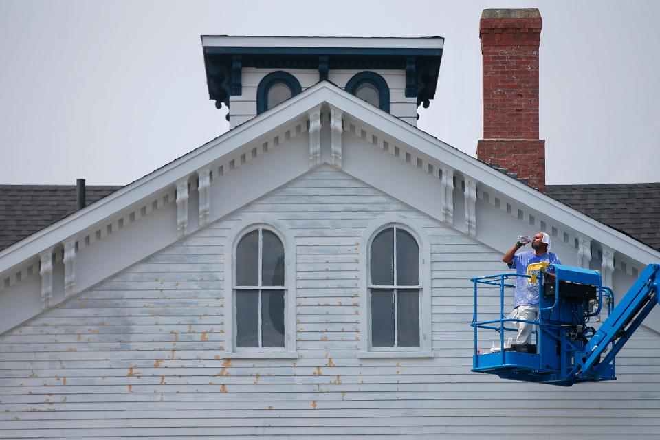 A painter working on a home in downtown New Bedford takes a moment to cool off from the sweltering heat by drinking water.