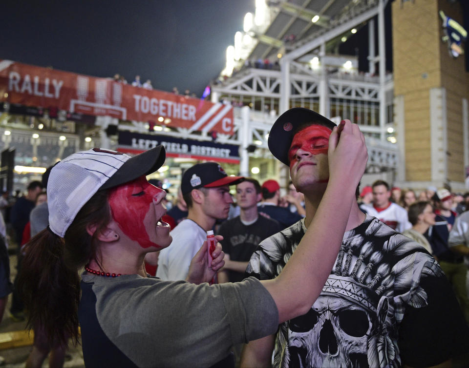 FILE - Cleveland Indians fan Leah Krankowski, left, paints the face of Chris Diz during a watch party for Game 7 of the baseball World Series between the Indians and the Chicago Cubs, outside Progressive Field in Cleveland, in this Wednesday, Nov. 2, 2016, file photo. While moving forward with a plan to change their name, the Cleveland Indians said they will not permit fans inside Progressive Field wearing headdresses or inappropriate face paint. The team announced the new guidelines on Wednesday, March 31, 2021, in advance of Monday's home opener against Detroit. (AP Photo/David Dermer, File)