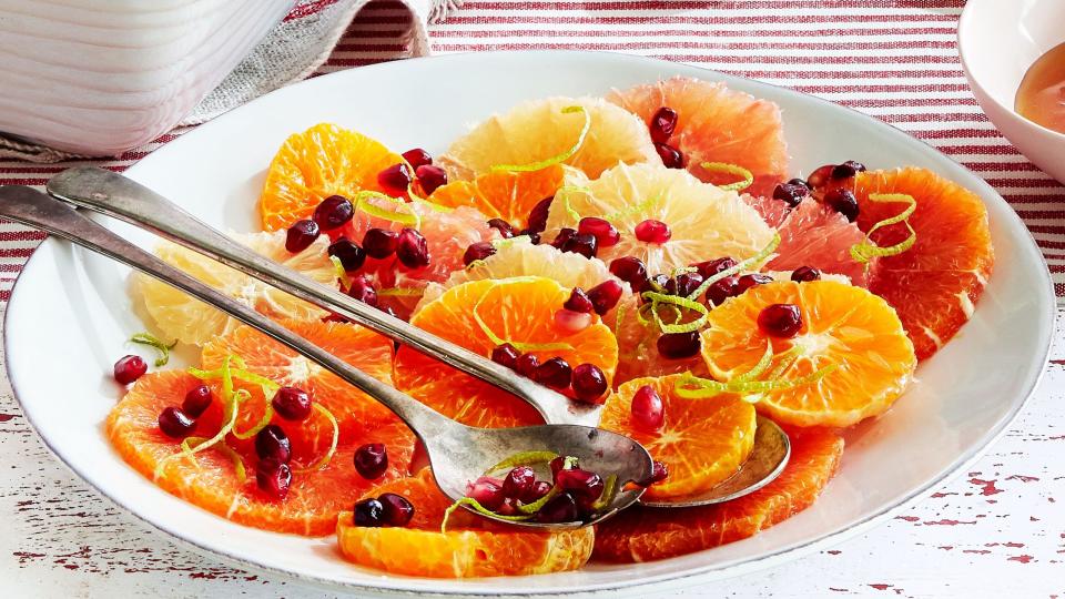 citrus slices on a platter with pomegranate seeds and lime rinds to garnish