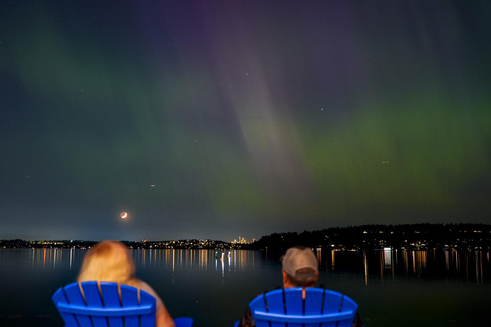 People view the northern lights, or aurora borealis, as they glow over Lake Washington, in Renton, Wash. Brilliant purple, green, yellow and pink hues of the Northern Lights were reported worldwide, with sightings in Germany, Switzerland, London, and the United States and Canada. (AP Photo/Lindsey Wasson)