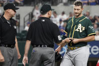 Oakland Athletics relief pitcher Burch Smith has his glove and hat checked by the umpires after he pitches in the sixth inning against the Texas Rangers in a baseball game Tuesday, June 22, 2021, in Arlington, Texas. (AP Photo/Louis DeLuca)