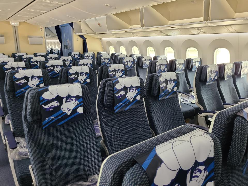 Inside Pokemon plane cabin with rows of seats with a subtle Pikachu design on top of chair