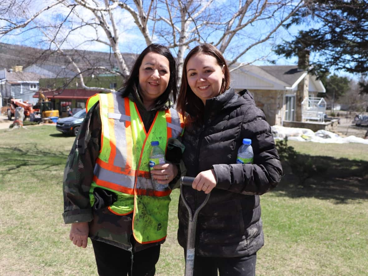 Manon Tremblay, left, and her daughter Audrey Simard, right, are part of a group of 600 volunteers that have been helping residents in Baie-Saint-Paul, Que., clean up and save whatever possessions they can after severe spring flooding overwhelmed the municipality earlier this week.   (Émilie Warren/CBC - image credit)