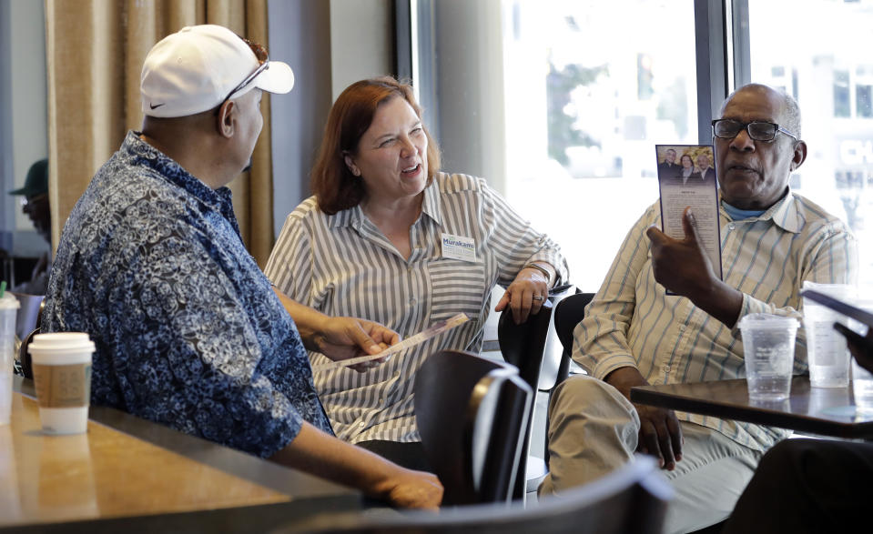 In this photo taken Monday, June 10, 2019, Seattle City Council candidate Pat Murakami, center, talks with voters in a coffee shop about her campaign in Seattle. A first-of-its-kind public campaign finance program in Seattle gives voters vouchers worth $100 to pass on to any candidate they want. Now in its second election cycle, advocates say the program can level the political playing field, although its first round in Seattle showed mixed results. (AP Photo/Elaine Thompson)