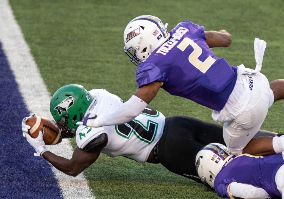 North Dakota running back Otis Weah (26) dives in under James Madison linebacker Diamonte Tucker-Dorsey (2) for a touchdown during the first half of a quarterfinal game in the NCAA FCS football playoffs in Harrisonburg, Va., Sunday, May 2, 2021. (Daniel Lin/Daily News-Record via AP)