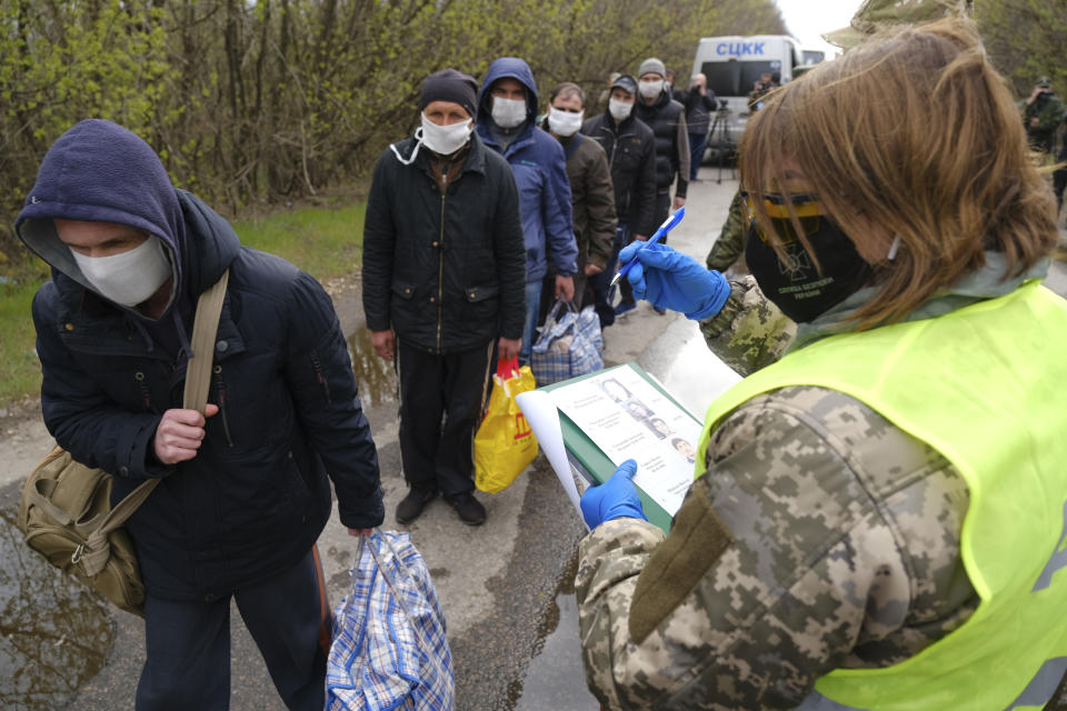 Russia-backed separatists war prisoners wearing masks to protect against coronavirus walk during a prisoner exchange, near Gorlivka, Donetsk region, eastern Ukraine, Thursday, April 16, 2020. Ukrainian forces and Russia-backed rebels in eastern Ukraine have begun exchanging prisoners in a move aimed at ending their five-year-long war. (Ukrainian Presidential Press Office via AP)