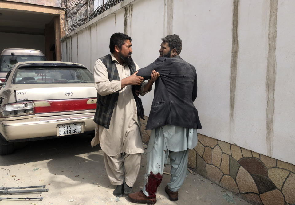 An Afghan man helps an injured man after a bomb blast in Mazar-e-Sharif, the capital city of Balkh province, in northern Afghanistan, Saturday, March 11, 2023. A bomb exploded on Saturday during an award ceremony for journalists in the city. (AP Photo/Abdul Saboor Sirat)