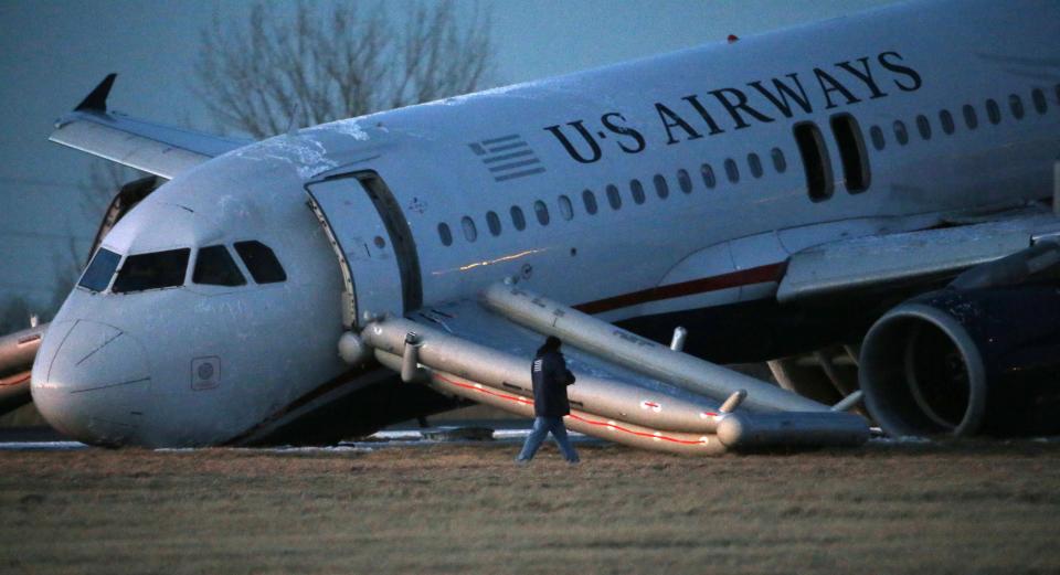A person walks around a damaged US Airways jet at the end of a runway at the Philadelphia International Airport, Thursday, March 13, 2014, in Philadelphia. Airline officials said the flight was heading to Fort Lauderdale, Fla., when the pilot was forced to abort takeoff around 6:30 p.m., after the front landing gear failed. An airport spokeswoman said no injuries have been reported. (AP Photo/Matt Slocum)