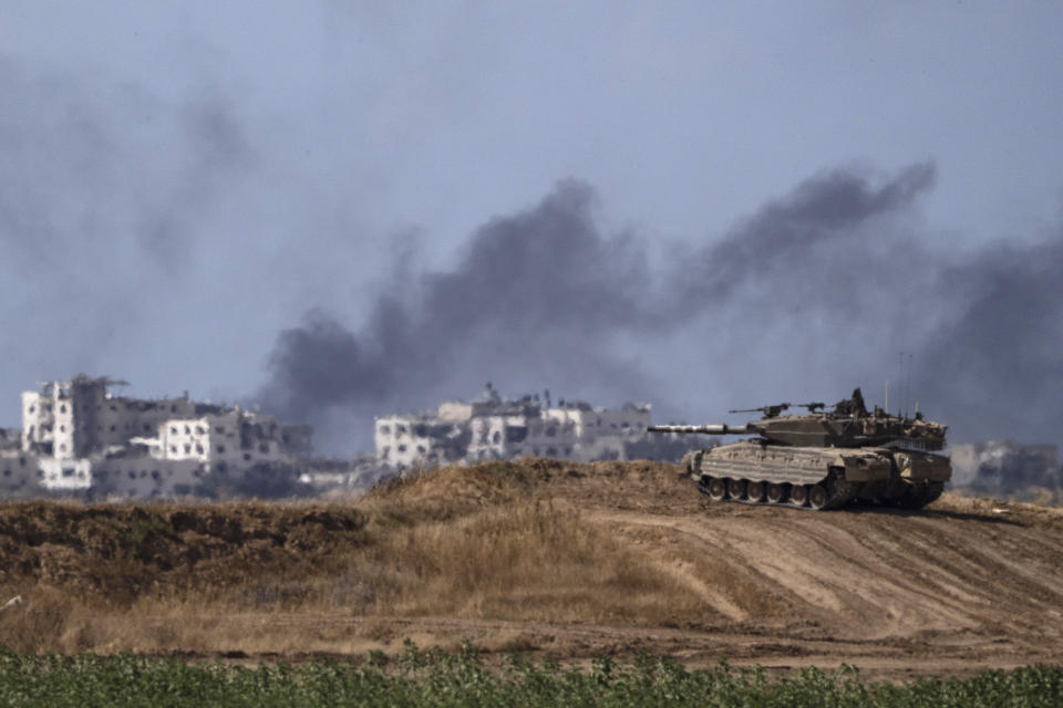 Backdropped by smoke rising to the sky after an explosion in the Gaza Strip, an Israeli tank stands near the Israel-Gaza border as seen from southern Israel, Monday, May 13, 2024. (AP Photo/Leo Correa)