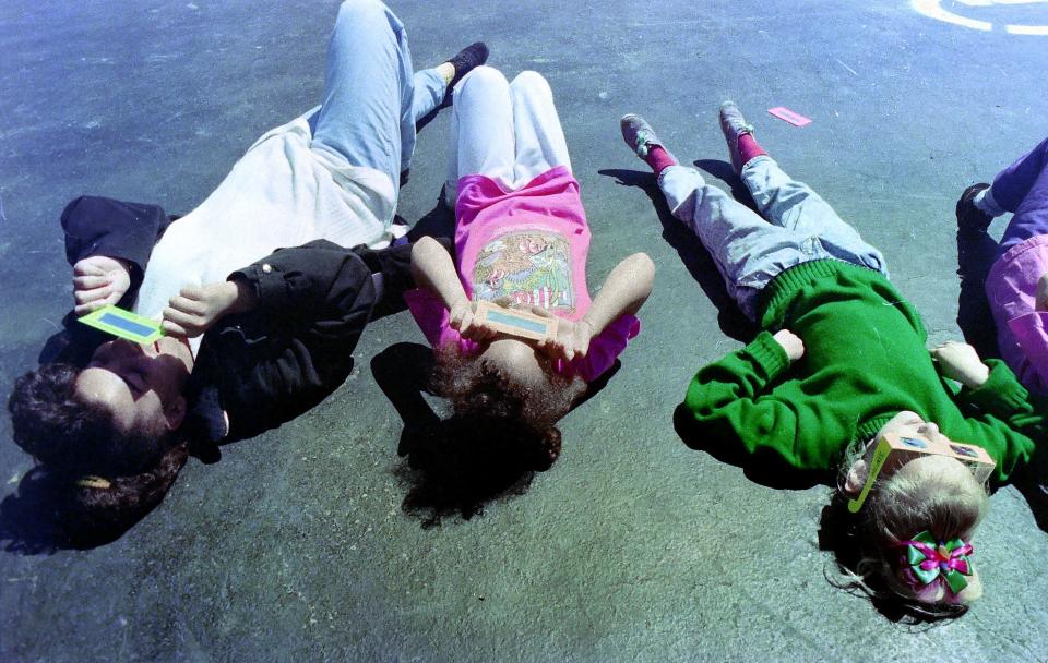 Seventh Day Adventist Church school students, left, to right, Amanda McCullum, Alyssa McCullum and Tonya Kostenko use protective glasses to watch a partial solar eclipse on May 10, 1994.