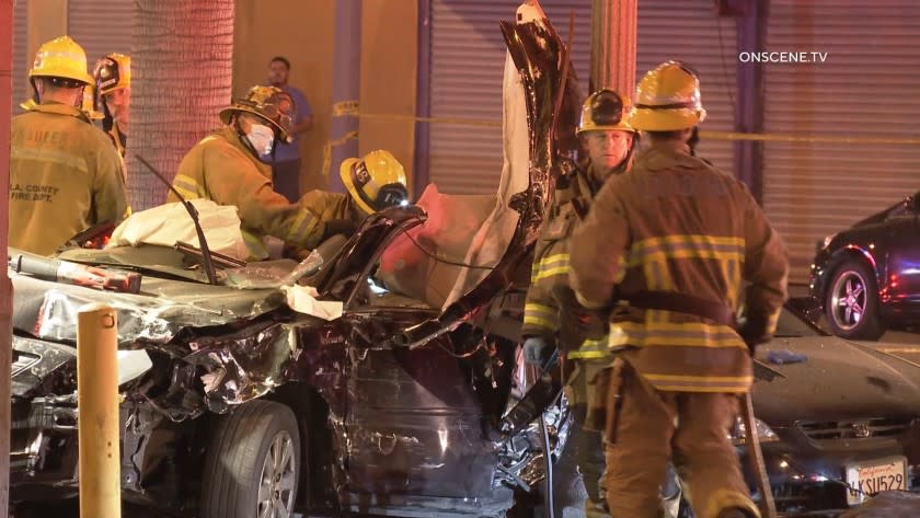 Firefighters attend to the crushed black sedan.