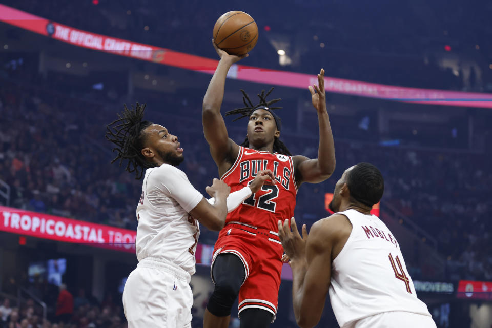Chicago Bulls guard Ayo Dosunmu (12) shoots against Cleveland Cavaliers guard Darius Garland, left, and forward Evan Mobley (4) during the first half of an NBA basketball game, Saturday, Feb. 11, 2023, in Cleveland. (AP Photo/Ron Schwane)