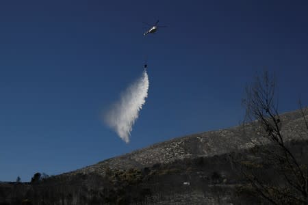 A firefighting helicopter makes a water drop during a wildfire on Mount Hymettus, near Athens