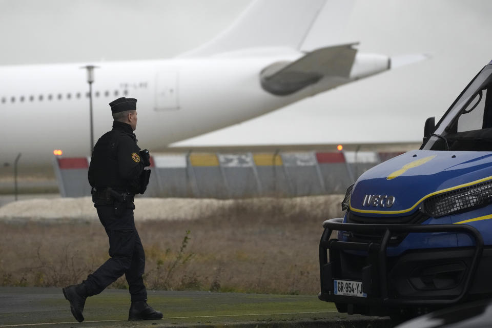 A Gendarme walks in front the plane which reportedly carried some 300 Indian citizens, at the Vatry airport, Saturday, Dec. 23, 2023 in Vatry, eastern France. About 300 Indian citizens heading to Central America were sequestered in a French airport for a third day Saturday because of an investigation into suspected human trafficking, authorities said. The 15 crew members of the Legend Airlines charter flight en route from United Arab Emirates to Nicaragua were questioned and released, according to a lawyer for the small Romania-based airline. (AP Photo/Christophe Ena)