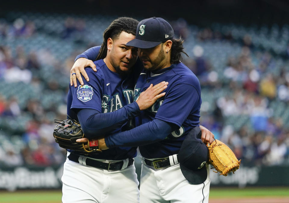 Seattle Mariners starting pitcher Luis Castillo, left, is hugged by third baseman Eugenio Suarez, right, as they walk back to the dugout after the fifth inning of a baseball game, against the Oakland Athletics, in which Castillo recorded 1,000th career strikeout Monday, May 22, 2023, in Seattle. (AP Photo/Lindsey Wasson)