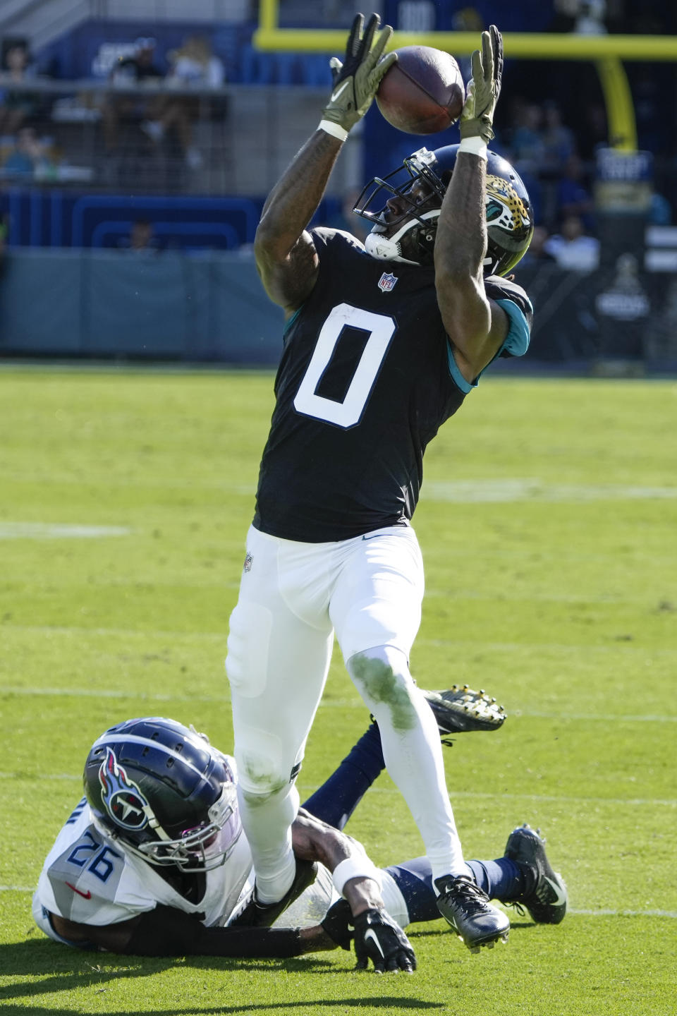 Jacksonville Jaguars wide receiver Calvin Ridley (0) makes a catch past Tennessee Titans cornerback Kristian Fulton (26) during the first half of an NFL football game, Sunday, Nov. 19, 2023, in Jacksonville, Fla. (AP Photo/John Raoux)