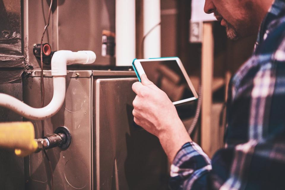 Home Inspector using digital tablet to inspect furnace