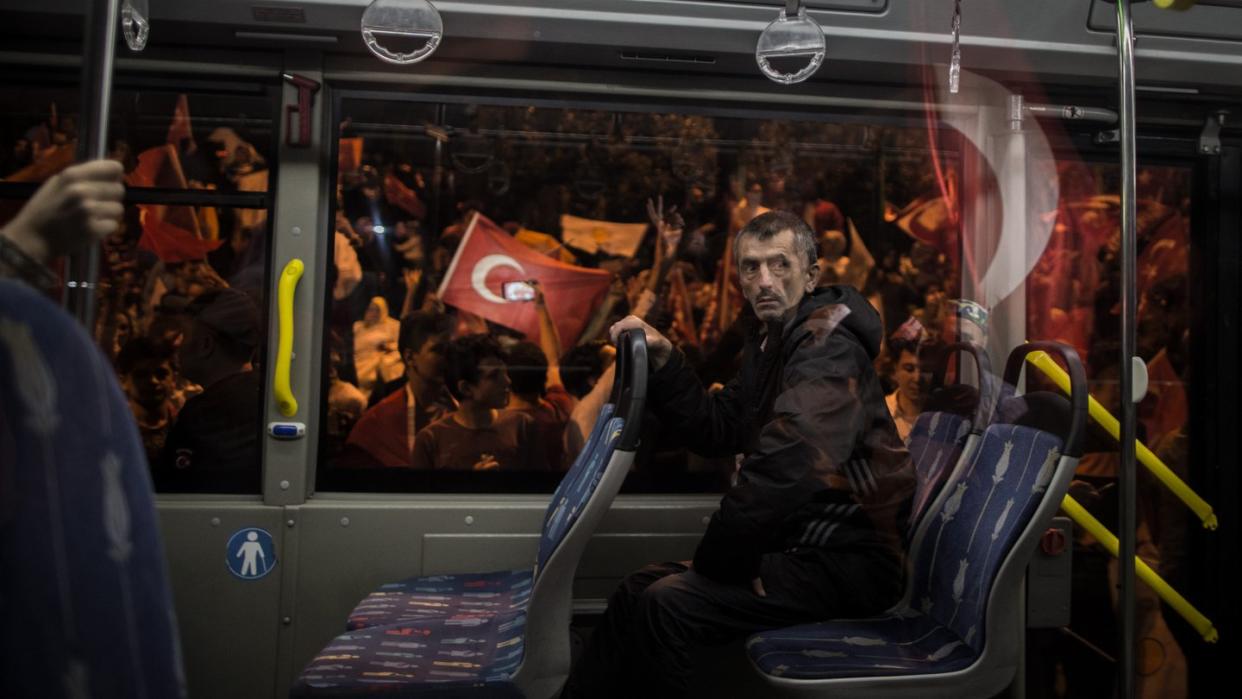 Ein Mann in einem Bus fährt an Anhängern des türkischen Präsidenten Erdogan vorbei, die auf der Straße in Istanbul jubeln. Foto: Oliver Weiken