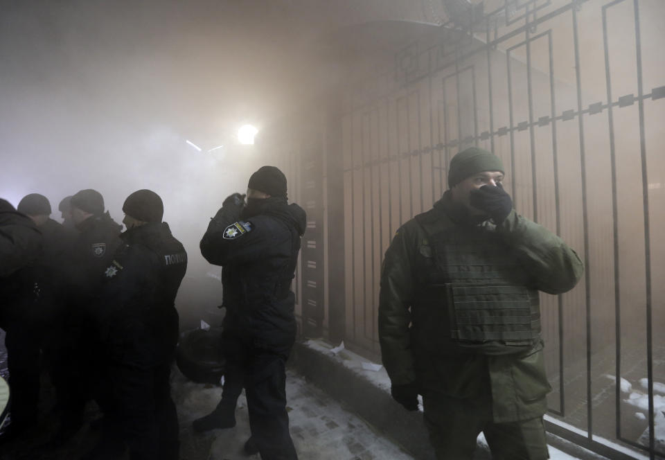Ukrainian policemen guard the Russian embassy building with smoke behind during a rally in Kiev, Ukraine, Sunday, Nov. 25, 2018. Russia's coast guard opened fire on and seized three of Ukraine's vessels Sunday, wounding two crew members, after a tense standoff in the Black Sea near the Crimean Peninsula, the Ukrainian navy said. (AP Photo/Efrem Lukatsky)