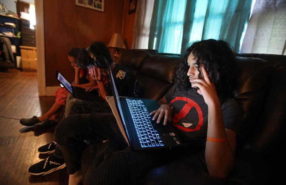 Ninth grader Reinaldo Sepulveda quietly attends his math class in May while sharing the living room couch with siblings Jeremiah and Rihanna in Rochester, N.Y.
