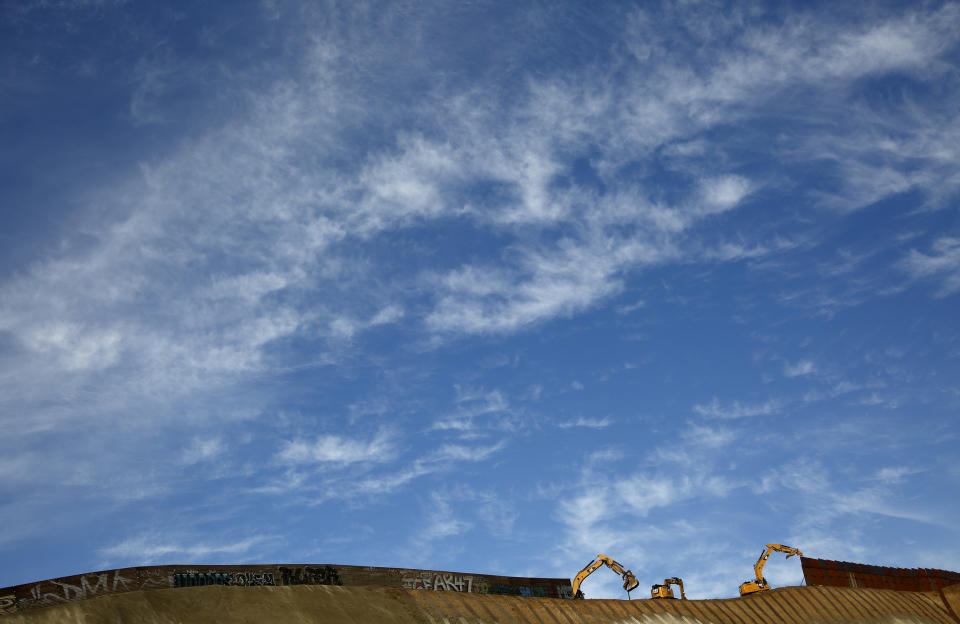 Workers replace sections of the border wall, left, with new sections, right, on Jan. 8, 2019, in Tijuana, Mexico. (AP Photo/Gregory Bull)