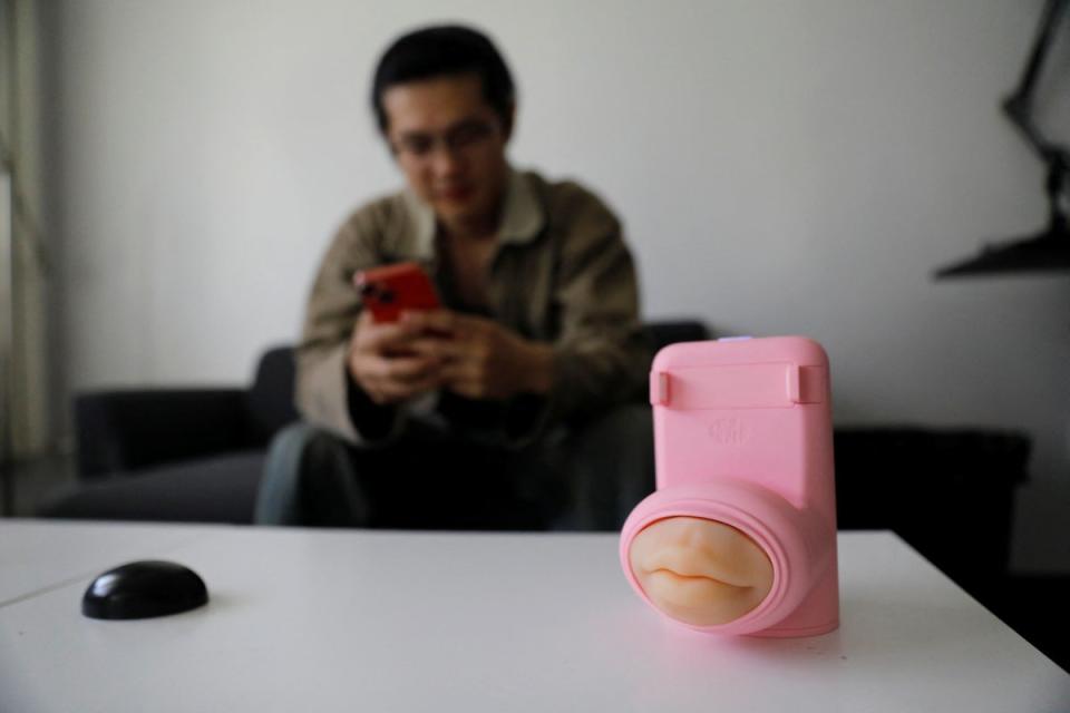 Jing Zhiyuan uses his phone near the remote kissing device (REUTERS)