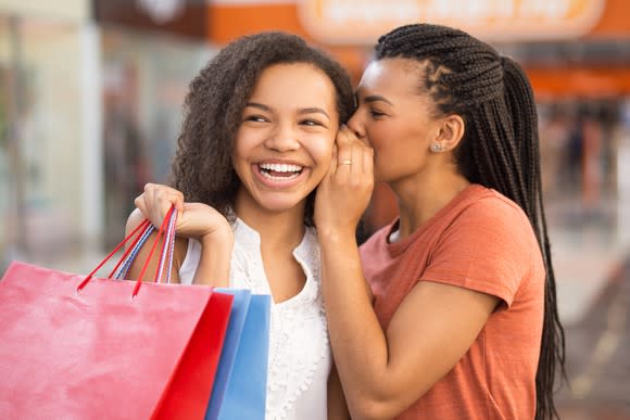 Two women sharing a secret while shopping