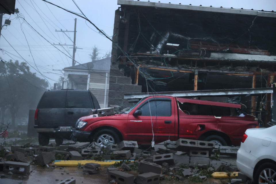 Damaged vehicles next to a partially collapsed building.