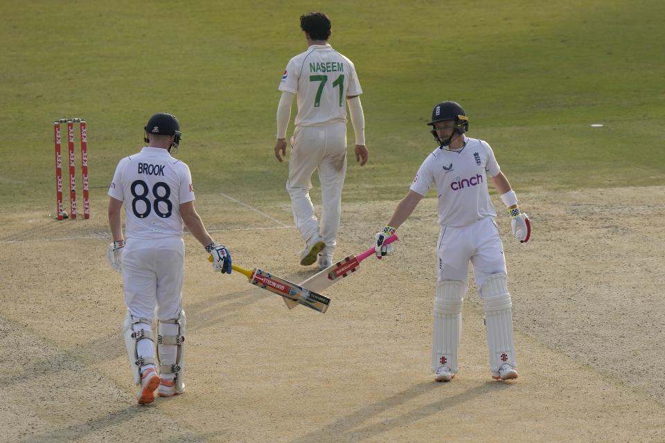 England's Ollie Pope, right, celebrates with teammate Harry Brook, left, after hitting a boundary during the first day of the first test cricket match between Pakistan and England, in Rawalpindi, Pakistan, Dec. 1, 2022. (AP Photo/Anjum Naveed)