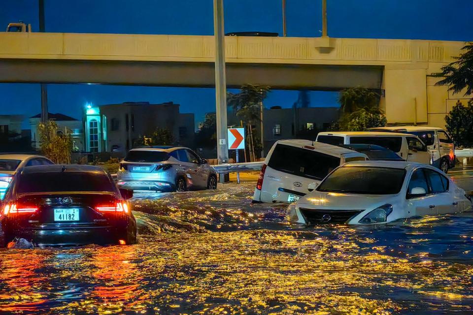 Cars drive in a flooded street following heavy rains in Dubai (AFP via Getty Images)