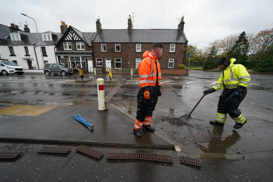 Workmen clear the drains in the village of Edzell, Scotland (PA)